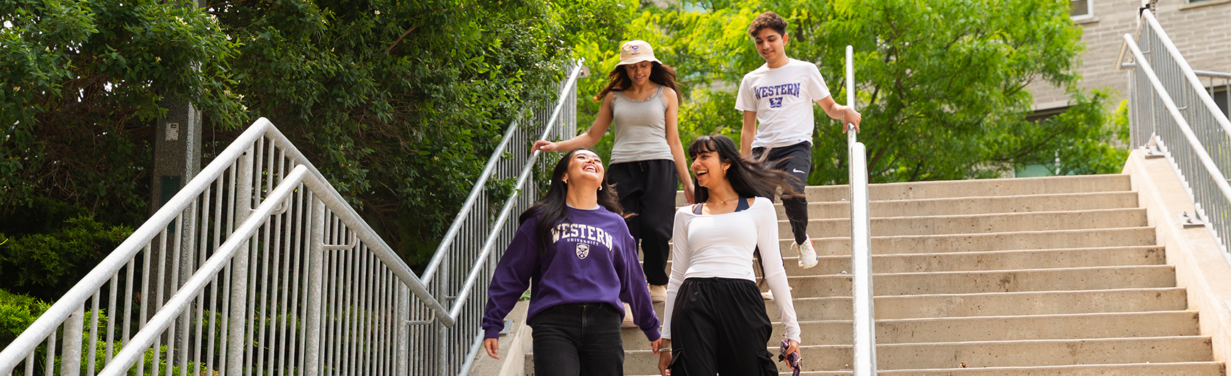 Four students walking down a set of stairs outside