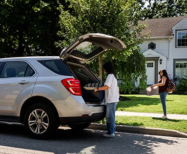 Two people removing items from the trunk of a car